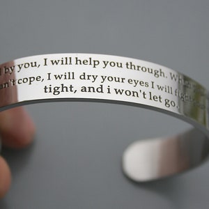 May include: A silver bracelet with an engraved message that reads: "I will stand by you, I will help you through. When you can't cope, I will dry your eyes I will fight tight, and I won't let go."