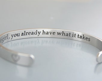 May include: Silver bangle bracelet with an engraved message that reads "Girl, you already have what it takes".