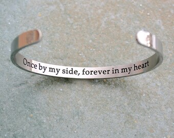 May include: Silver bracelet with the inscription "Once by my side, forever in my heart".