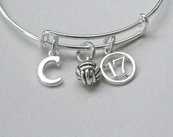 May include: Silver charm bracelet with a volleyball charm, a letter C charm, and a charm with the number 17.