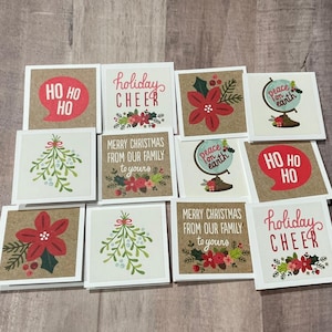 May include: A collection of square Christmas cards with various designs and text. Some cards feature "HO HO HO" in a speech bubble, "Holiday Cheer", poinsettias, mistletoe, and a globe with "peace on earth". Other cards read "Merry Christmas from our family to yours".