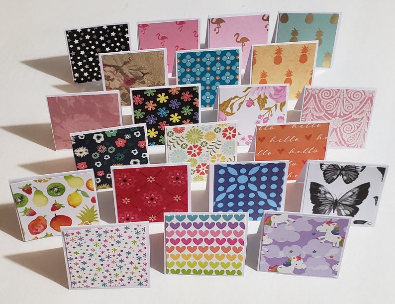 Op de afbeelding: Een verzameling van 20 vierkante kaarten met verschillende patronen en ontwerpen. De kaarten zijn in verschillende kleuren, waaronder roze, blauw, groen, rood, geel en zwart. Sommige van de patronen omvatten sterren, harten, bloemen, vlinders en ananas.