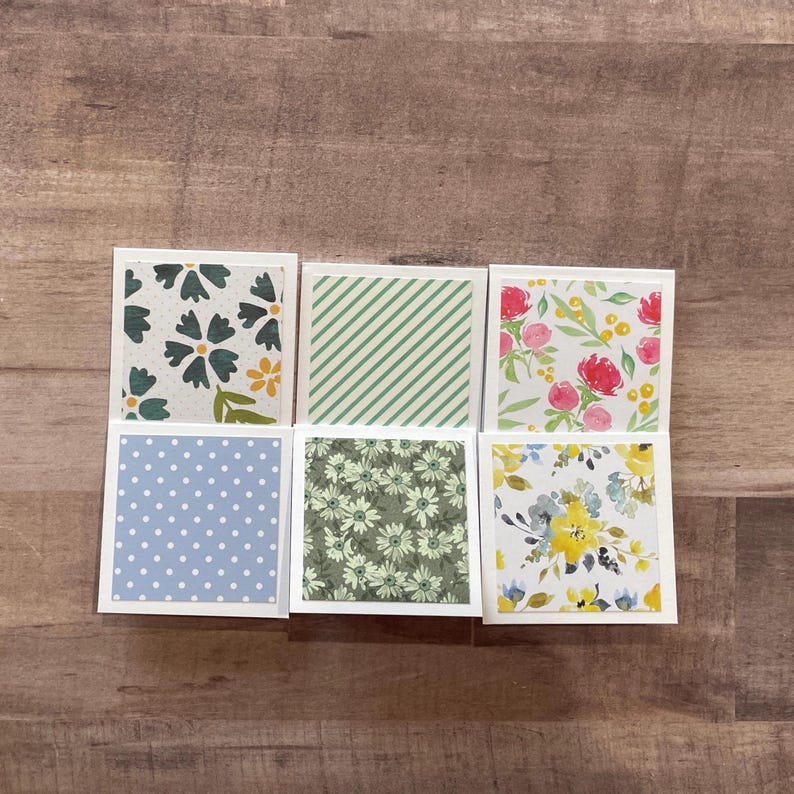 May include: A set of three ceramic mugs with a speckled, matte finish. Each mug features a different color: light blue, cream, and gray. The mugs have a simple, modern design and a comfortable handle.