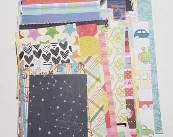 May include: A stack of colorful patterned paper scraps for scrapbooking or crafting. The papers feature various designs, including stars, hearts, and geometric patterns.
