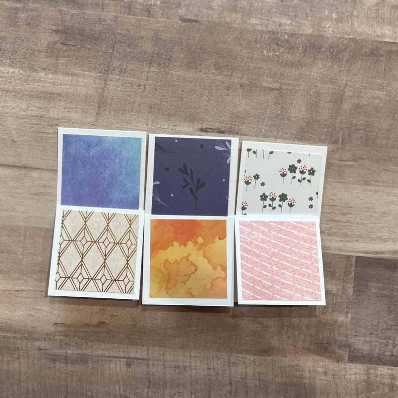May include: Six small, square cards with decorative patterns. The top row features a blue watercolor, a navy floral, and a white floral design. The bottom row shows a gold geometric, an orange watercolor, and a pink diagonal stripe pattern.