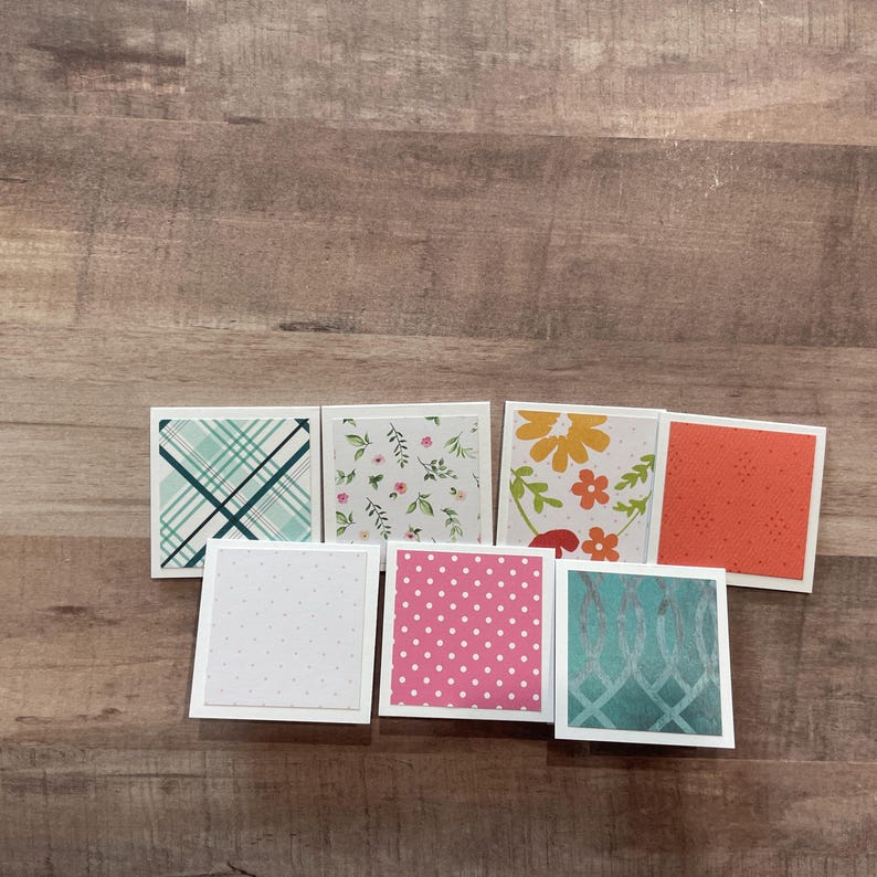 May include: A collection of square cards with various patterns. Designs include teal plaid, floral, polka dots, and geometric patterns in colors like pink, orange, and teal. Each card has a white border.