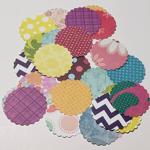 May include: A collection of 20 scalloped paper circles with various colorful patterns, including polka dots, stripes, floral designs, and geometric shapes.