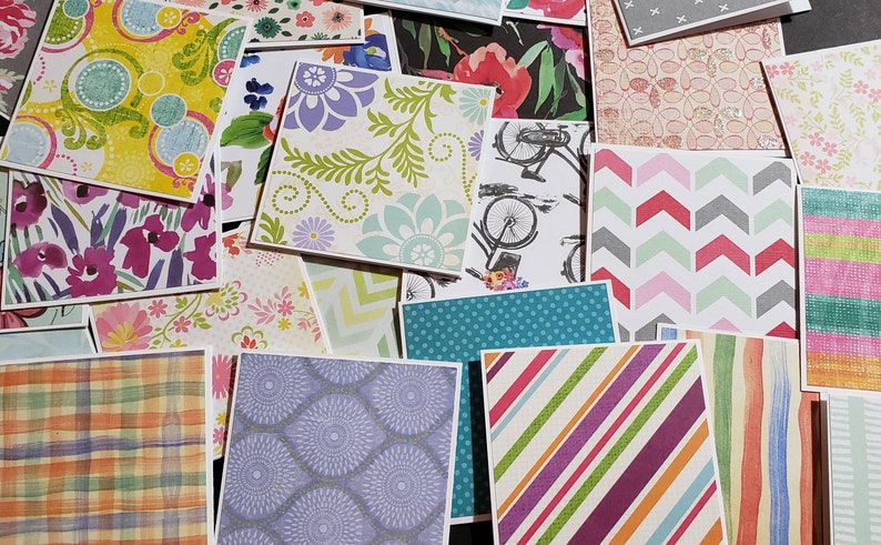 May include: Assortment of patterned paper squares with various designs, including floral, geometric, and abstract patterns. The papers are in a variety of colors, including pink, blue, green, yellow, and orange.