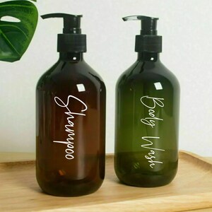 May include: Two amber glass bottles with black pump tops and white labels. The bottle on the left is labeled "Shampoo" and the bottle on the right is labeled "Body Wash".