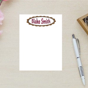 May include: A white notepad with a brown oval border and the text "Blake Smith" in red lettering.