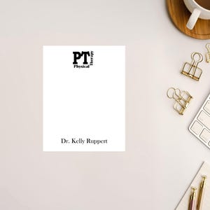 May include: A white notepad with black text that reads "PT Physical Therapy" and "Dr. Kelly Ruppert".