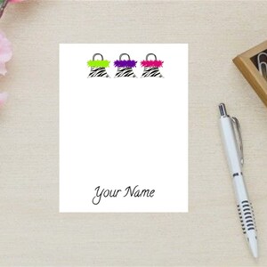 May include: A white notepad with three zebra-print purses with different colored fur trim. The notepad has the text "Your Name" at the bottom.