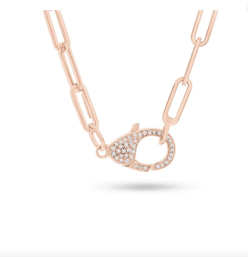 May include: A rose gold chain necklace with a pave diamond clasp. The chain is made of linked rectangles.
