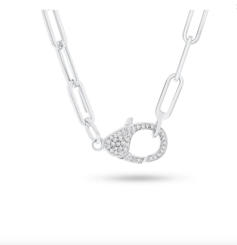 May include: A silver chain necklace with a silver clasp that is encrusted with small clear stones.