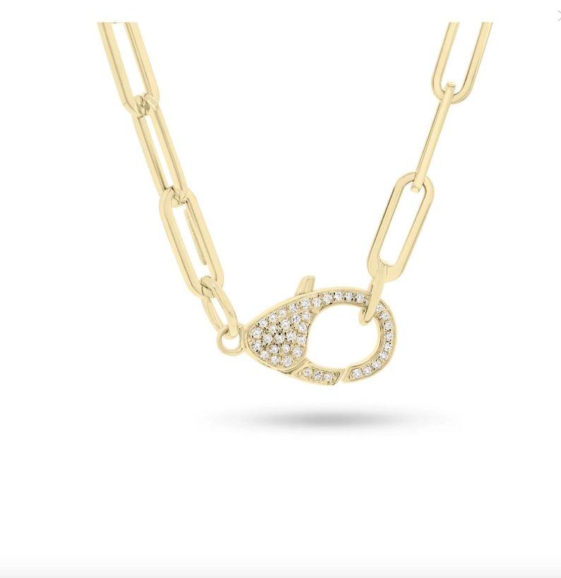 May include: A gold chain necklace with a pave diamond clasp. The chain is made of linked ovals.