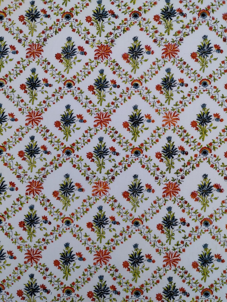 May include: A white background with a repeating pattern of blue, orange, and green floral designs. The floral designs are arranged in a diamond pattern.