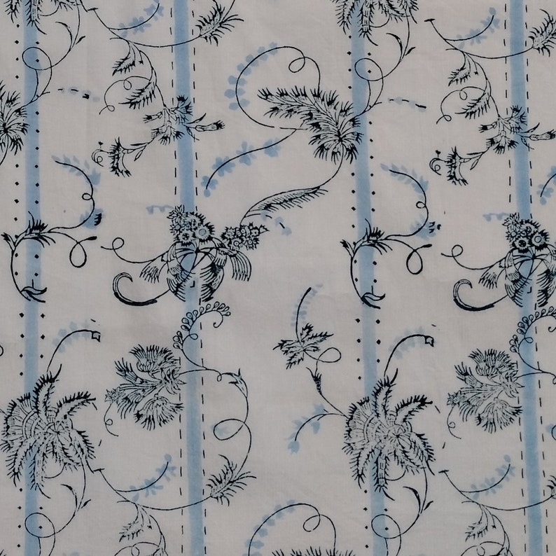 Light blue stripes on white fabric with dark blue floral and foliage designs twisting around. The design is a hand made block print with a half brick repeat.