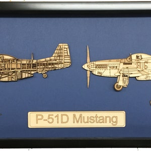 以下が含まれることがあります： P-51D Mustang の木製模型が額装されています。機体の内部が断面で表示されています。模型は青い背景に置かれ、その下に「P-51D Mustang」の文字があります。