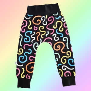 May include: Black baby pants with a colorful swirl pattern in pink, yellow, blue, and orange. The pants have a black waistband and cuffs. The design is playful and eye-catching, suitable for infants and toddlers.