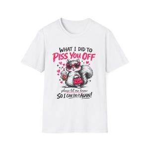 Puede incluir: Camiseta blanca con un gráfico de una ardilla con gafas de sol en forma de corazón, sosteniendo una taza de café y un bolso rosa. El texto dice: "WHAT I DID TO PISS YOU OFF, please let me know SO I CAN DO IT AGAIN!"