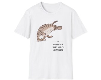 May include: White t-shirt featuring a cartoon cat in a napping pose. The cat is brown and tan with stripes. Text on the shirt reads, "Napping is a sport, and I'm an athlete."