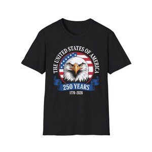 Puede incluir: Camiseta negra con un diseño gráfico de un águila calva americana, el texto "THE UNITED STATES OF AMERICA" y "250 YEARS 1776-2026" en un diseño circular con la bandera americana.