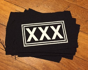 May include: A stack of black fabric patches with a white border and the text "XXX" in white.