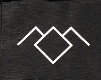May include: Black fabric patch with a white geometric design. The design features a central diamond shape flanked by two mountain-like triangles. The patch has a textured surface.
