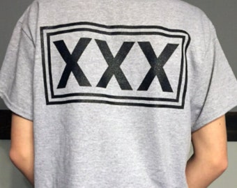 May include: A gray t-shirt with a black rectangular box containing the text "XXX" printed on the back.