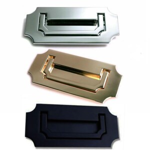 May include: Three door handles in different finishes: chrome, brass, and black. Each handle is rectangular with a decorative edge and a recessed opening.
