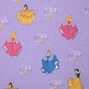 May include: A light purple fabric featuring a repeating pattern of Disney princesses in yellow, pink, and blue ballgowns. The design includes white cursive text that reads Princess, small gold crown icons, and faint white outlines of castle silhouettes.