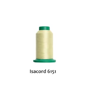 Puede incluir: Una bobina de hilo verde claro con una bobina de plástico verde. La etiqueta en la parte inferior dice "Isacord 6151".