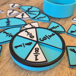 May include: A set of turquoise fraction manipulatives with black and white details. The set includes a circular base divided into fractions, along with individual fraction pieces. A small turquoise cup is also present. Educational tools for math.