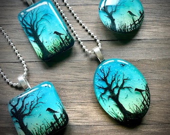 May include: Four glass pendants with silver chains, each featuring a hand-painted watercolor scene of a silhouetted tree with birds in a blue and green gradient.