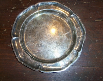 May include: A silver-plated serving tray with a scalloped edge. The tray is round and has a smooth, reflective surface.