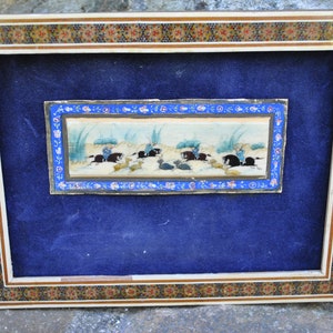 May include: A framed miniature painting depicting a scene of horseback riding. The painting is set against a blue background and features a blue, white, and gold frame with intricate floral designs.