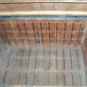 May include: The inside of a wooden crate with a blue painted exterior. The crate has a wire mesh lining and a wooden bottom.
