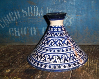 Könnte beinhalten: Ein weißer Keramik-Tagine-Deckel mit einem blau-weißen geometrischen Muster. Der Deckel ist rund und hat eine konische Spitze.