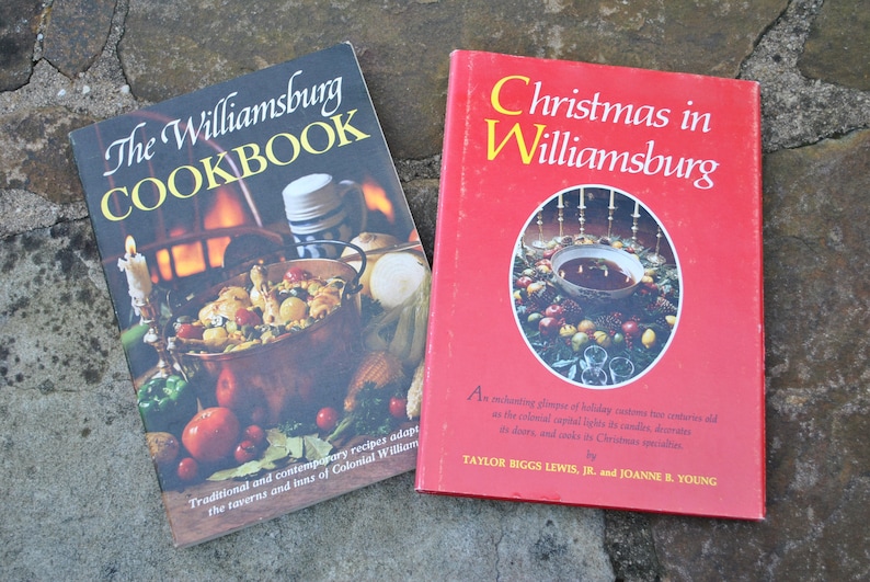 May include: Two vintage cookbooks with red and black covers. The first book is titled "The Williamsburg Cookbook" and features a copper pot with food inside. The second book is titled "Christmas in Williamsburg" and features a red bowl with a Christmas wreath around it.