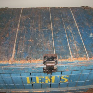 May include: A vintage wooden crate painted blue with the word "LEM'S" in yellow letters. The crate has a metal hinge and is weathered with age.