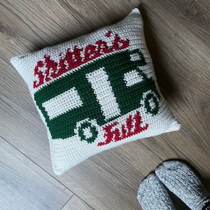 May include: A white crocheted pillow with the words "Santa's Sleigh is Full" in red and a green and white crocheted image of a sleigh.