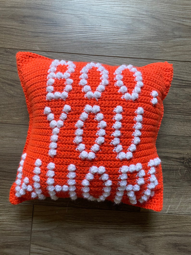 May include: Orange crocheted pillow with the words "Do you love me" in white crocheted letters.