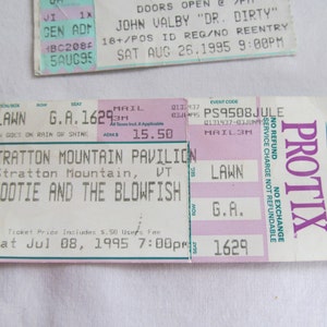 May include: A pink and white ticket for a concert at Stratton Mountain Pavilion. The ticket is for a lawn seat, general admission, and costs $15.50. The concert is for Hootie and the Blowfish on Saturday, July 8, 1995 at 7:00 PM.