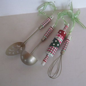 Puede incluir: Conjunto de cuatro utensilios de cocina con patrones de cuadros y lunares verdes y rosas. Los utensilios incluyen una cuchara para servir, una cuchara ranurada, un batidor y un rodillo.