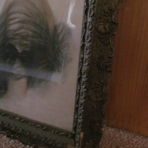 May include: A vintage picture frame with an ornate, dark brown wooden frame. The frame has a decorative design with intricate details.