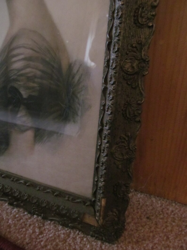 May include: A vintage picture frame with an ornate, dark brown wooden frame. The frame has a decorative design with intricate details.
