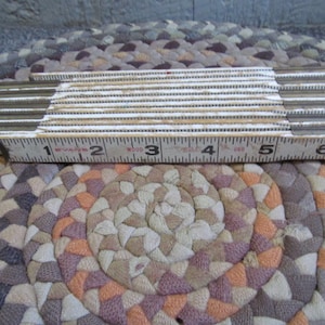 Pode incluir: Uma régua dobrável de madeira branca com marcas pretas e pontas metálicas. A régua está estendida para mostrar os números de 1 a 6.