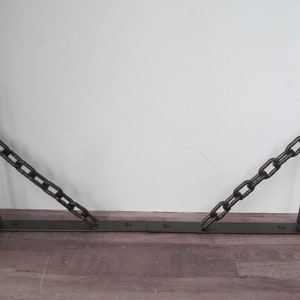 May include: Two black metal shelf brackets with a chain connecting the two brackets.