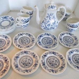 Puede incluir: Un juego de té floral azul y blanco con una tetera, tazas, platillos y una pila de platos.