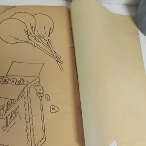 Puede incluir: Una p&aacute;gina de libro para colorear vintage con una ilustraci&oacute;n en blanco y negro de una caja de palomitas de ma&iacute;z Cracker Jack con la tapa abierta y las palomitas de ma&iacute;z derram&aacute;ndose. Hay tres globos atados juntos con cuerdas sobre la caja.